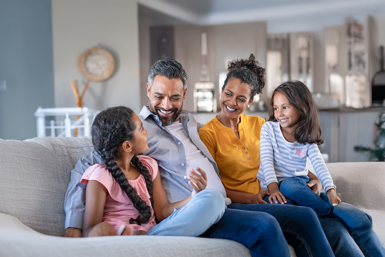A happy family of four sitting on a sofa, embracing health resolutions for a vibrant New Year.